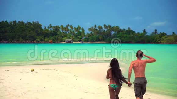 慢镜头跨种族的幸福夫妇在阳光明媚的夏日在热带海滩享受蜜月视频的预览图