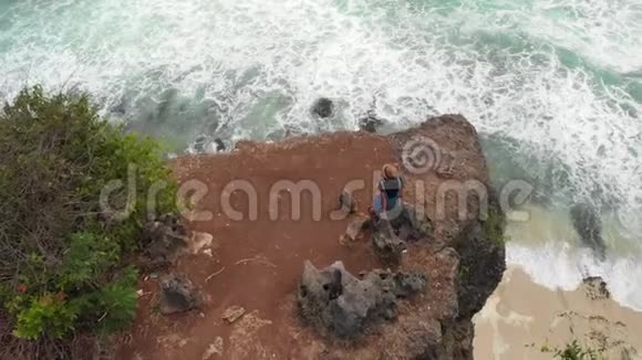 4K航天无人机镜头快乐健康浪漫的女人坐在悬崖上美的出行运动理念巴厘视频的预览图