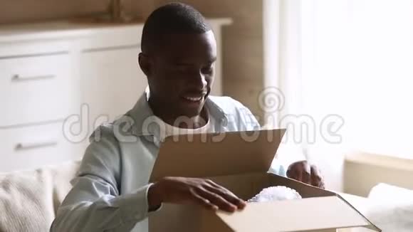 快乐的非洲人客户打开包裹纸板箱在家视频的预览图