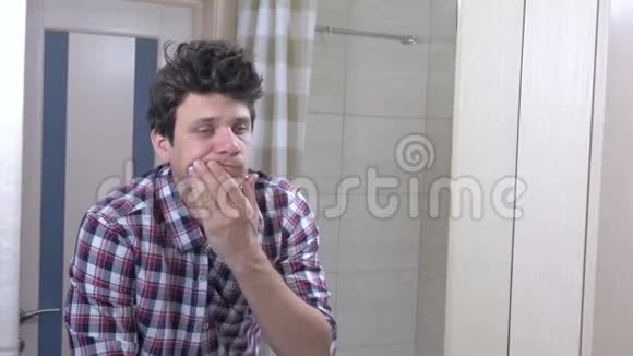 疲惫的睡醒男人在浴室里宿醉整理好自己把补丁贴在眼睛下面视频的预览图