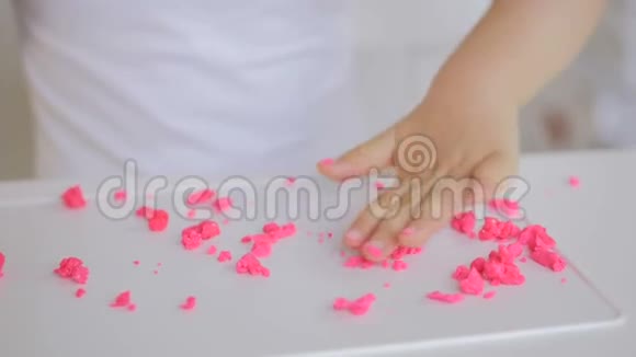 一个小女孩坐在一个房间的桌子上用粉红色的塑料制成雕像手和手指的特写视频的预览图