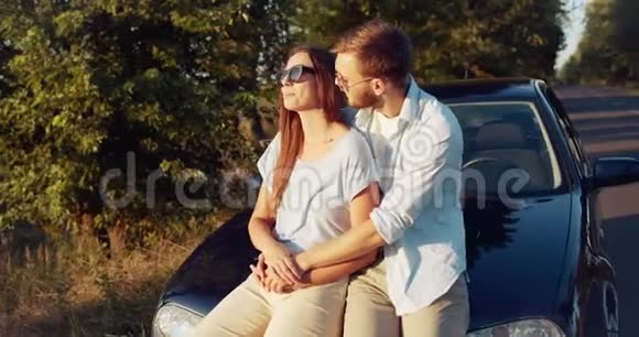 幸福的夫妻坐在车上日落视频的预览图