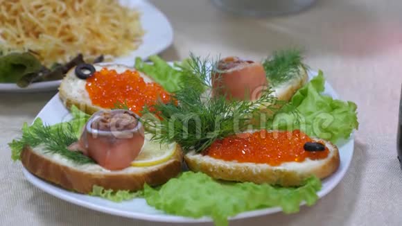 三明治里有红鱼和红鱼子酱盘子里还有沙拉节日餐桌美味的食物视频的预览图