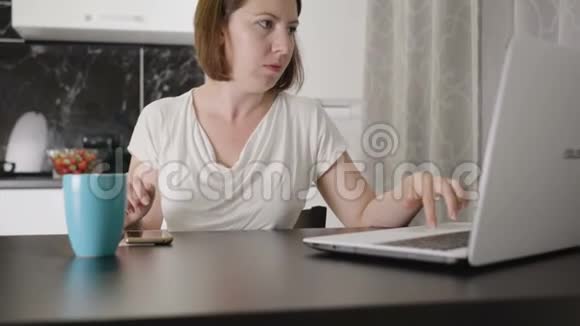 在家里桌子旁用笔记本电脑工作的女人视频的预览图