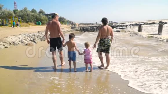 有孩子的年轻家庭在沙滩上散步手牵手视频的预览图