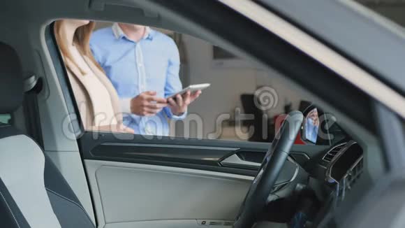 幸福的年轻女子检查汽车内饰并向推销员伸出大拇指视频的预览图