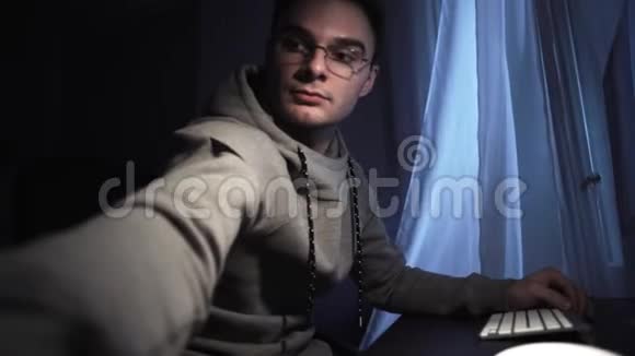 戴眼镜的年轻人坐在电脑里调整相机拍摄自己视频的预览图