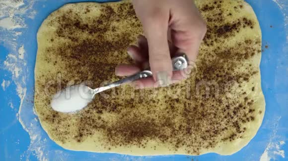 4K镜头面包师把一层糖洒在生酥面团上顶部视图视频的预览图