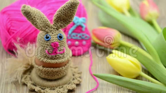 用羊毛做的钩针复活节兔子蛋杯背景的新鲜郁金香和羊毛球视频的预览图