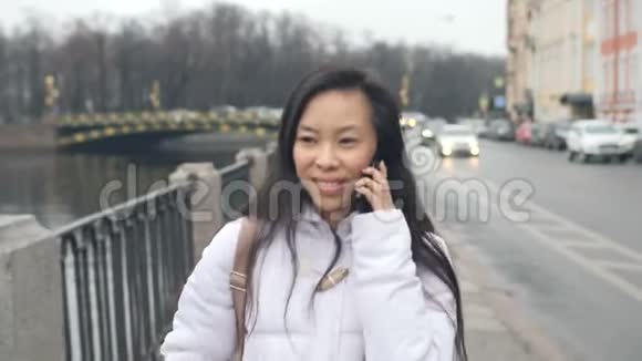 年轻的亚洲妇女在城市中谈论手机视频的预览图