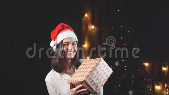 戴着圣诞老人帽子的快乐女孩手里拿着礼物慢动作视频的预览图