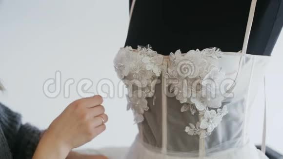 在他的工作室里为新娘准备时装设计师为婚纱扎针花边和鲜花裁缝创造视频的预览图