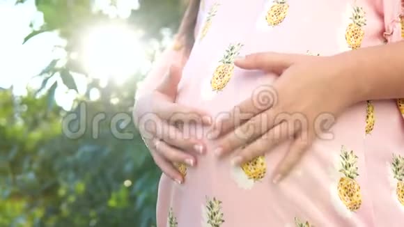 夕阳西下怀孕少女肚子上美丽的心视频的预览图