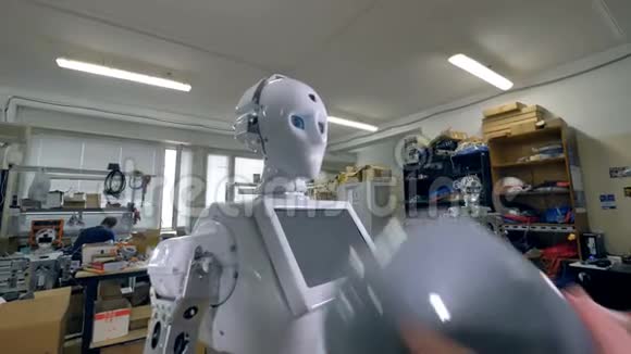 一位工程师把灰色塑料假发戴在机器人的头上视频的预览图