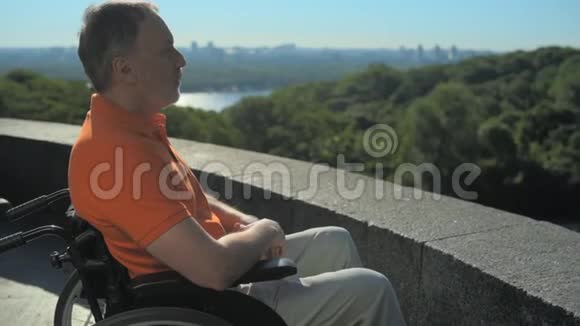 一个体贴的人坐在轮椅上欣赏城市景色视频的预览图