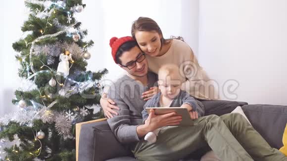 幸福的家庭拥抱在圣诞树的背景上视频的预览图