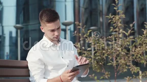穿着白色休闲衬衫带平板电脑的漂亮男人视频的预览图