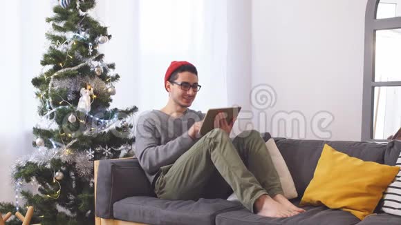 年轻人在圣诞树上玩平板电脑视频的预览图
