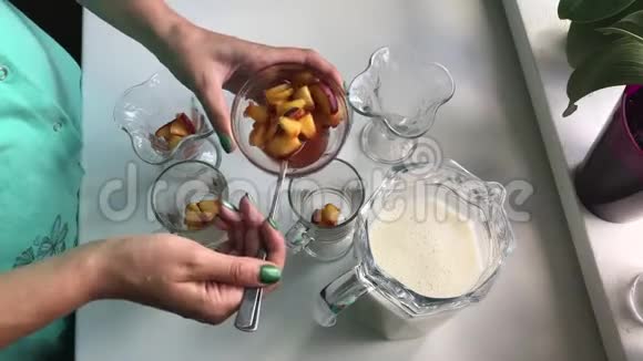 女人把桃子上的馅放在眼镜的底部一种美味的牛奶果冻里面装满了桃子视频的预览图