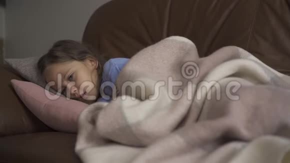生病的年轻白种人女孩在家里躺在毯子下咳嗽这孩子发烧了健康疾病概念视频的预览图