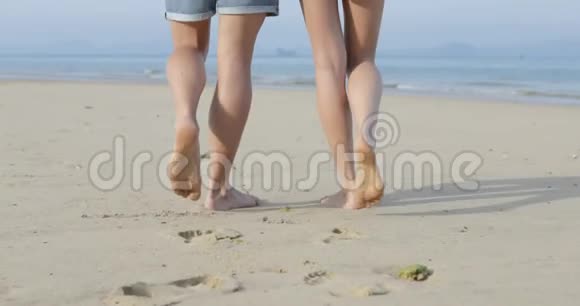 情侣在沙滩上散步到海边腿特写后景男人和女人视频的预览图
