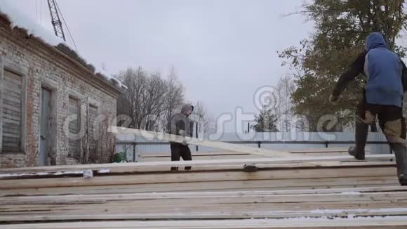 冬季白天在锯木厂院子里搬运木板的装载机视频的预览图