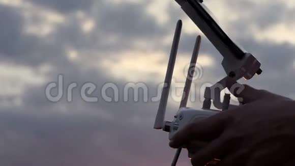 女人她手里拿着控制面板在日落时操作无人机视频的预览图