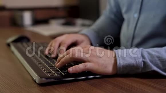 重要人物手里拿着蓝色衬衫在键盘上打字木制桌子机动滑块录像视频的预览图