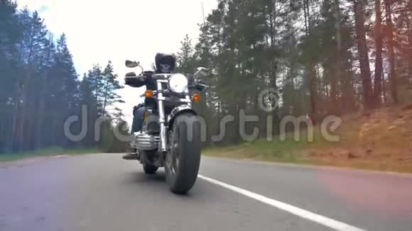 一辆骑着铺好的森林道路的摩托车上的低景视频的预览图