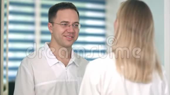 戴眼镜的男医生微笑着和女护士说话视频的预览图