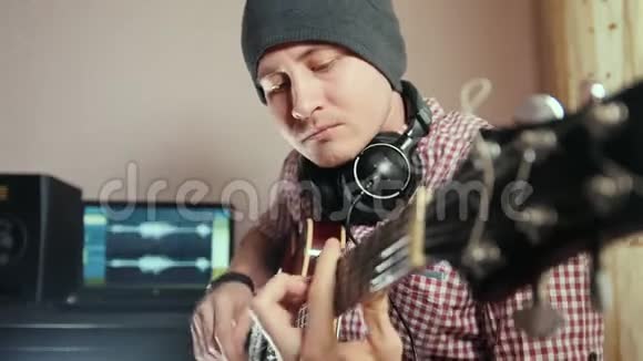 年轻有魅力的男音乐家用电脑作曲并录制弹吉他的配乐专注于脸部和面部视频的预览图