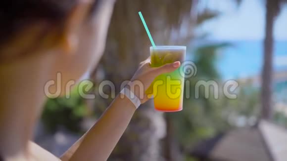 在阳光明媚的天气里一家靠近海边的酒店休息区域里女人拿着一杯鸡尾酒做了一个小的视频的预览图