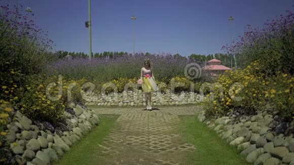 幸福的小姑娘正在花圃里散步可爱的梦中情人视频的预览图