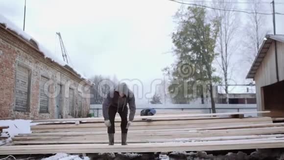 冬季白天在锯木厂院子里搬运木板的工人视频的预览图