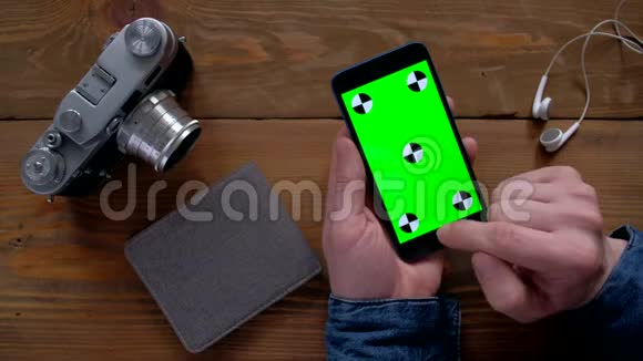 摄影师使用智能手机绿色屏幕在木桌上视频的预览图
