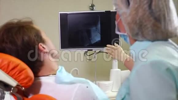女性牙医在屏幕上显示男性病人的x光扫描视频的预览图