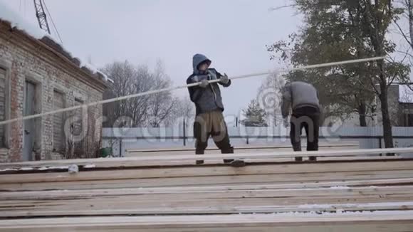 冬天搬运工在锯木厂院子里搬运木板视频的预览图