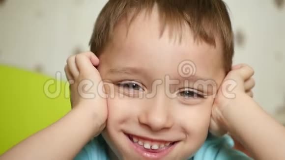 一个带着喜悦和微笑的孩子看着镜头双手抱在脑后闭上耳朵特写镜头视频的预览图
