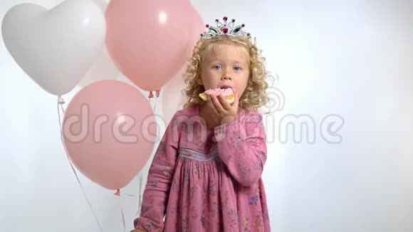 三岁的小女孩带着气球在生日时吃甜甜圈在白色背景下被隔离视频的预览图