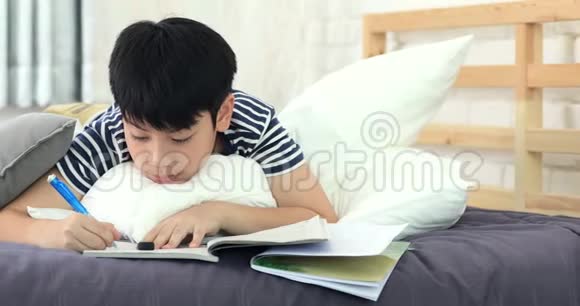 亚洲男孩在家做作业朋友休息在床上和看书视频的预览图