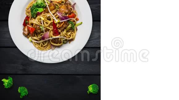 用肉或鸡肉和蔬菜旋转炒面用新鲜西兰花装饰在黑色木制的白色盘子里视频的预览图