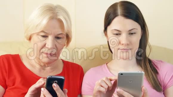 母女俩用智能手机浏览阅读新闻科技时代理念中的孤独视频的预览图