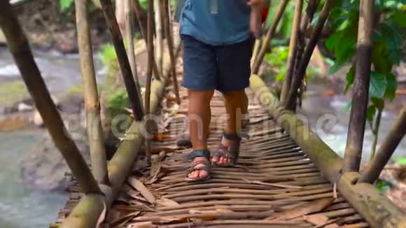 父亲在竹木桥上穿过热带河流视频的预览图