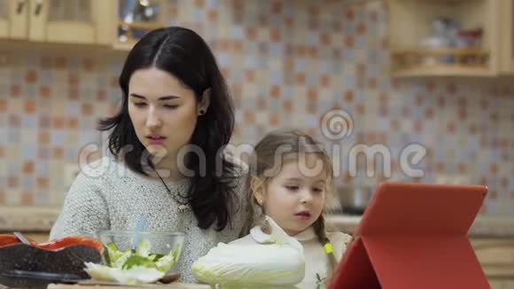 妈妈和小女儿坐在厨房的桌子旁视频的预览图
