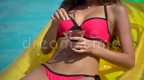 夏天美丽的年轻女子比基尼女孩在热带游泳池放松女人吃樱桃概念视频的预览图