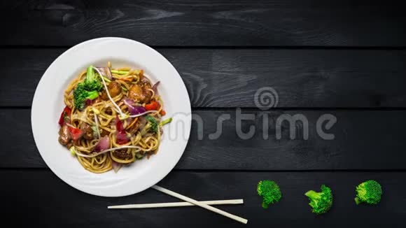 旋转乌冬炒面与肉或鸡和蔬菜用新鲜的西兰花和筷子装饰视频的预览图