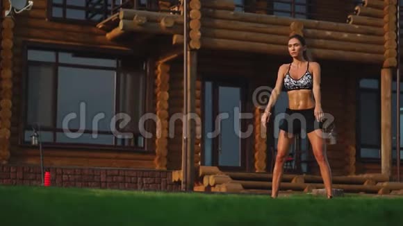 美丽的黑发女人在一个大豪宅的背景下从事健身房和表演蹲在露天锻炼视频的预览图