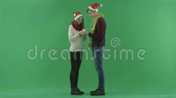 年轻夫妇在镜头前展示圣诞蜡烛背景上有彩色钥匙视频的预览图