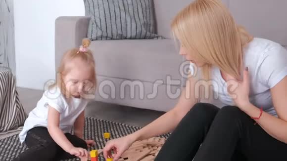 小可爱的金发女孩和妈妈坐在沙发附近玩木块视频的预览图