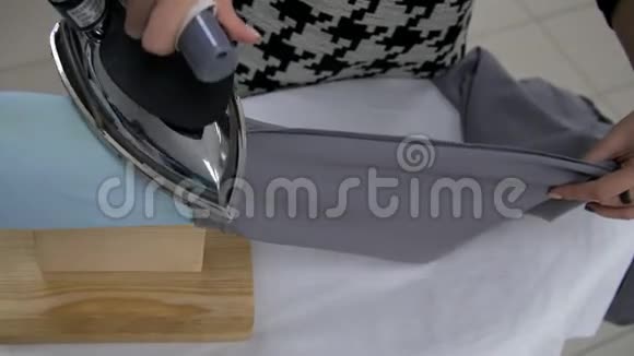 女孩用裁缝的熨斗熨灰色的织物视频的预览图